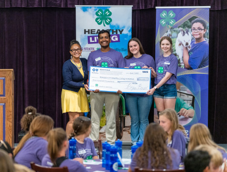 Charmekia Martin, director of growth and engagement for Healthy Blue, presenting a check to Kansas 4-H Youth Council Members Sukesh Kamesh, Emma Littich, and Elizabeth “Ellie” Seeger.