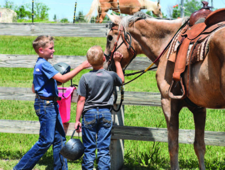Two youth campers care for a horse during Family Camp at Rock Springs Ranch this spring. Through the horse program, visitors to Rock Springs Ranch learn responsibility and horsemanship through the hands-on immersive experience.